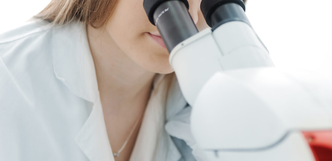 Beautiful female researcher using a microscope in a lab